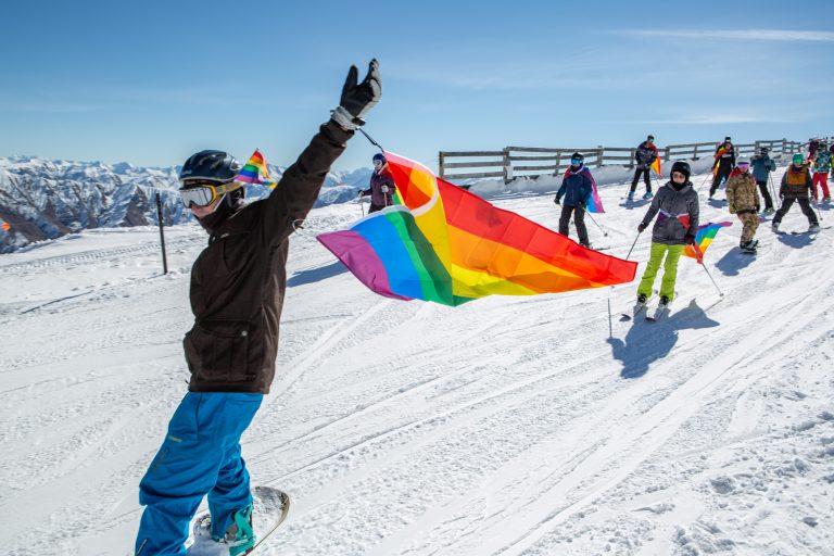 People Skiing through snow with pride flags