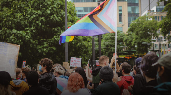 LGBTQIA+ pride flag waving in crowd of people outside